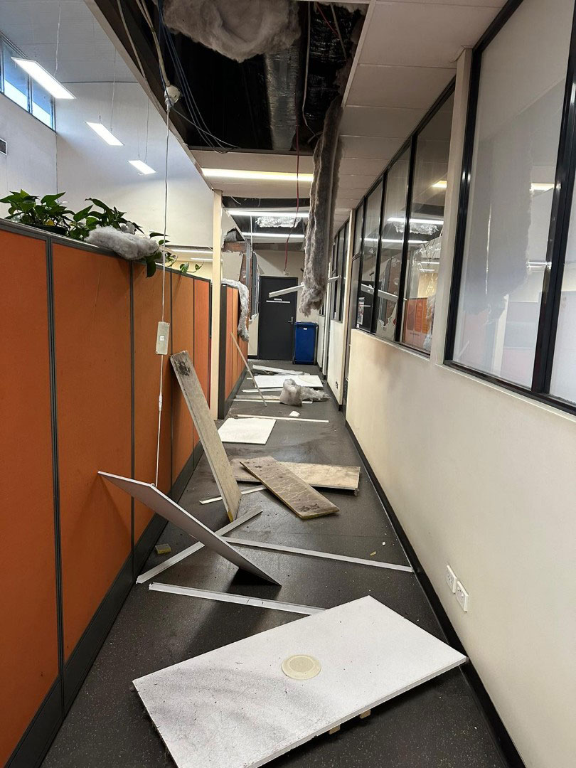 Ceiling collapse and debris in an office corridor following seismic activity, showing damage to non-structural elements.