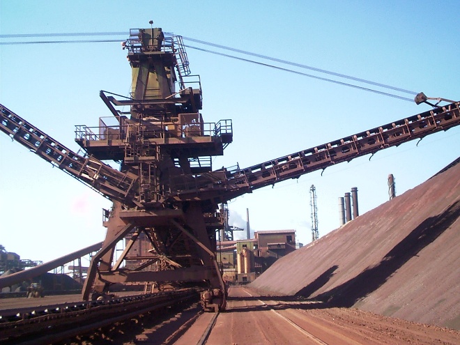 Front view of a fixed bat wing stacker with conveyor booms extending to both sides of the stockpile.