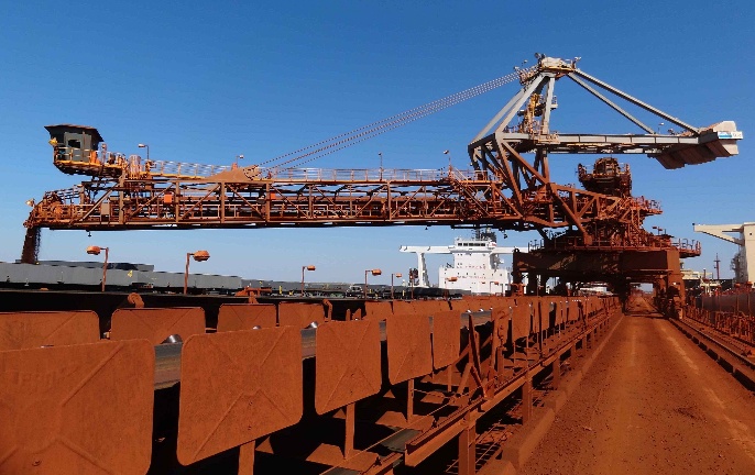 Portal slewing shiploader positioned alongside a bulk carrier at a port loading facility.